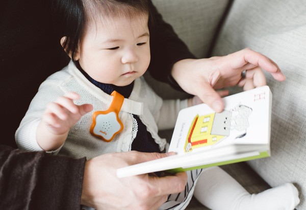 Baby with Starling device reading picture book with adult